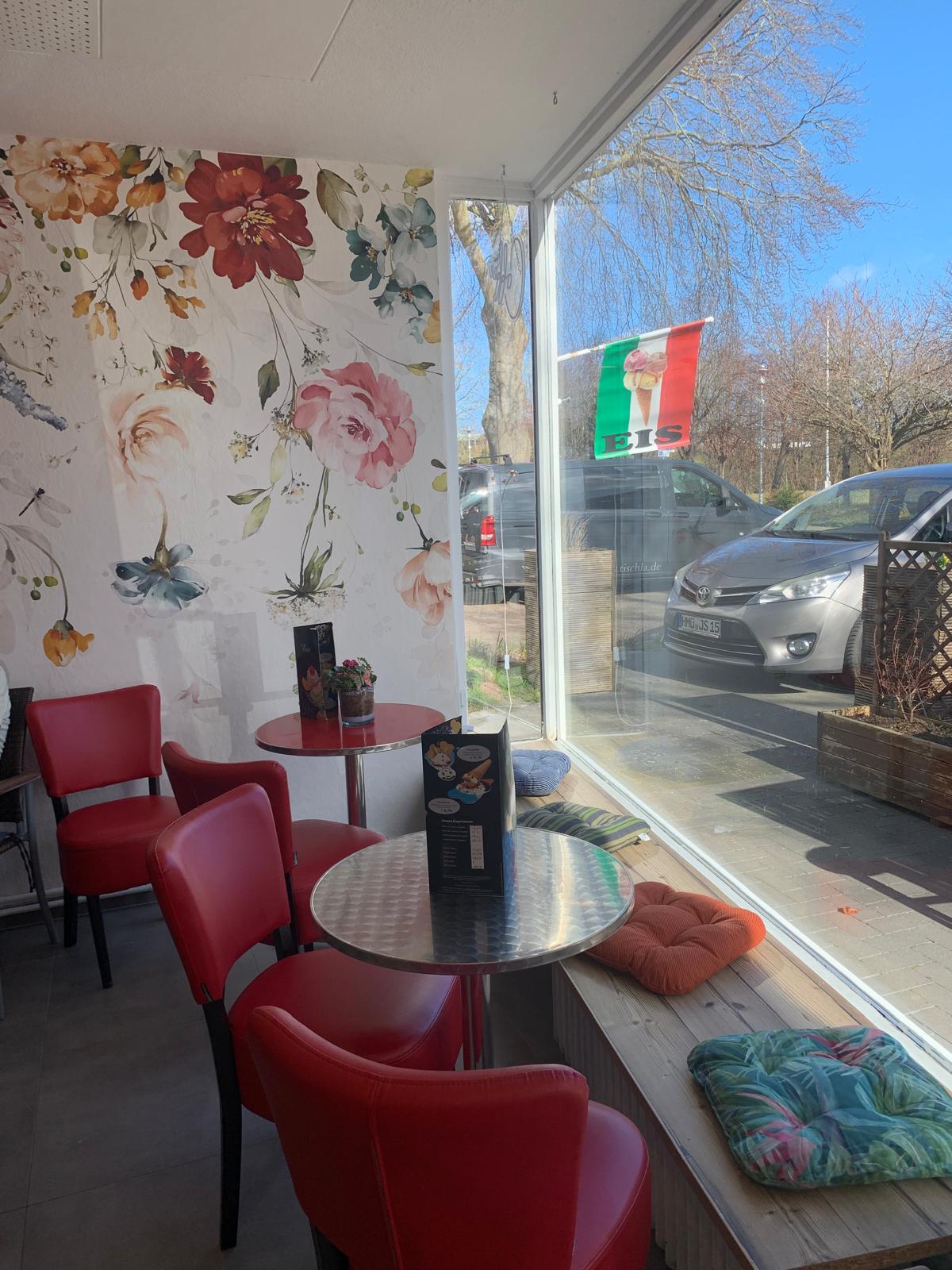 Sitzbereich am Fenster mit Blumenwand und Eis-Flagge